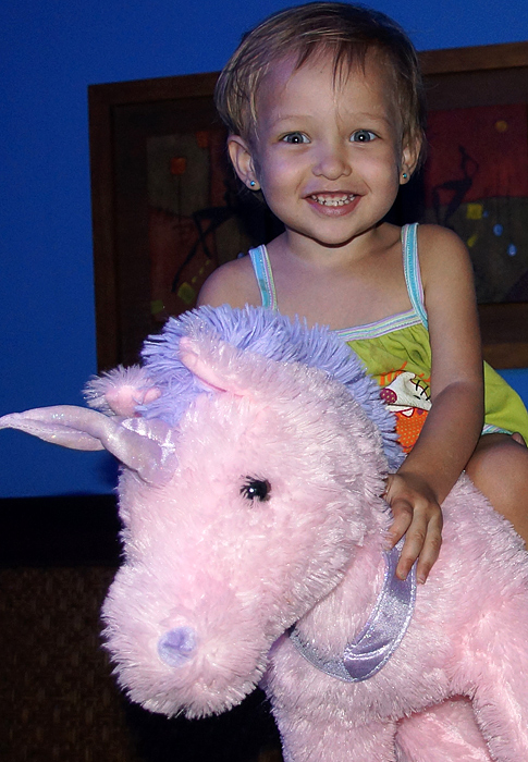 Bebé latina montando un unicornio rosado