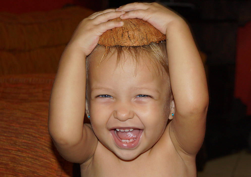 Bonita bebé poniendose una cascara de coco en su cabeza