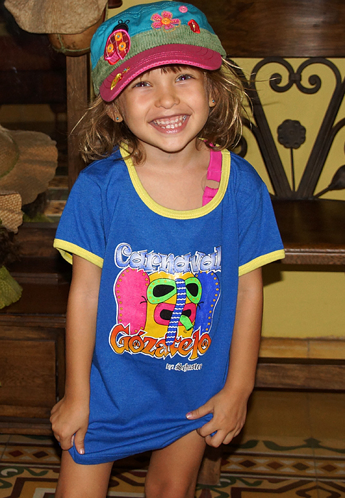 Hermosa y feliz niña rubia colombiana vestida con una camiseta azul colorida y gorra de carnaval